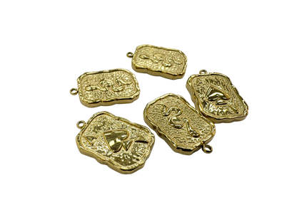 Five gold ace of spades pendants with embossed designs on a white background